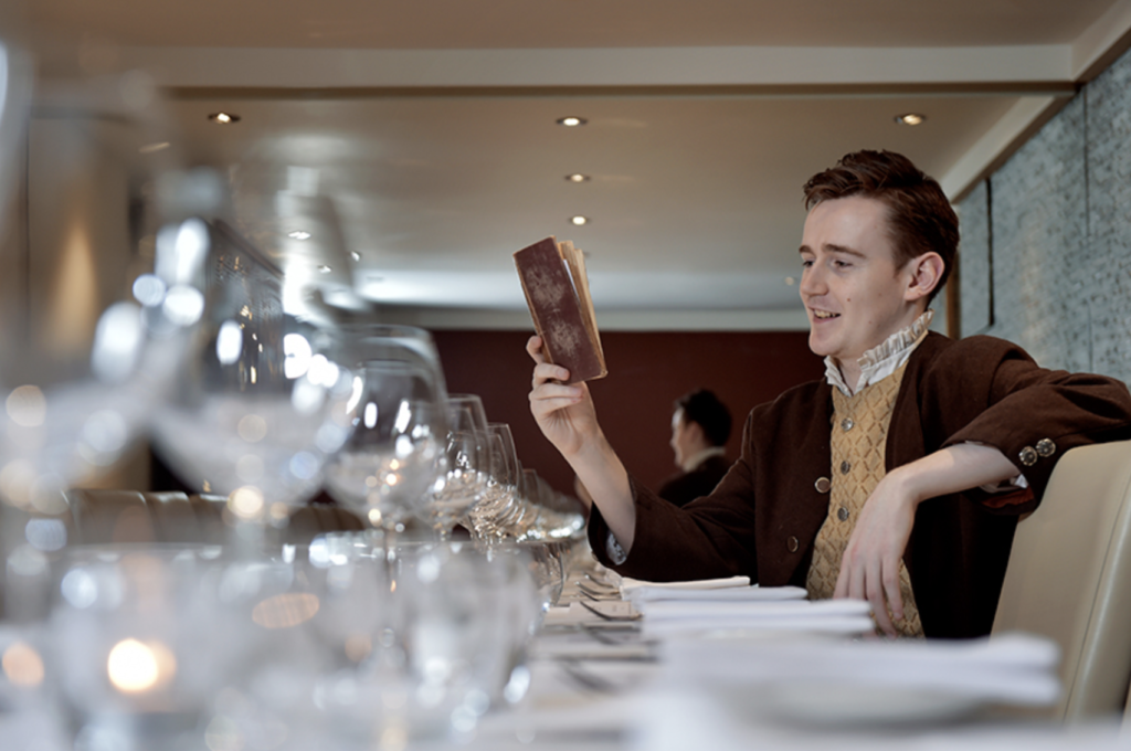 Man dressed as Burns smiling and reading